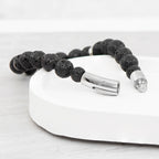 Black beaded bracelet with silver clasp on a white surface