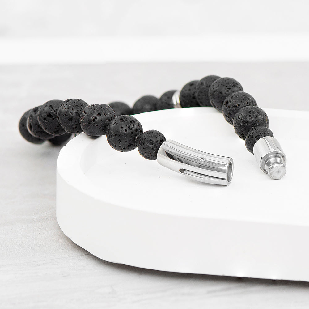 Black beaded bracelet with silver clasp on a white surface