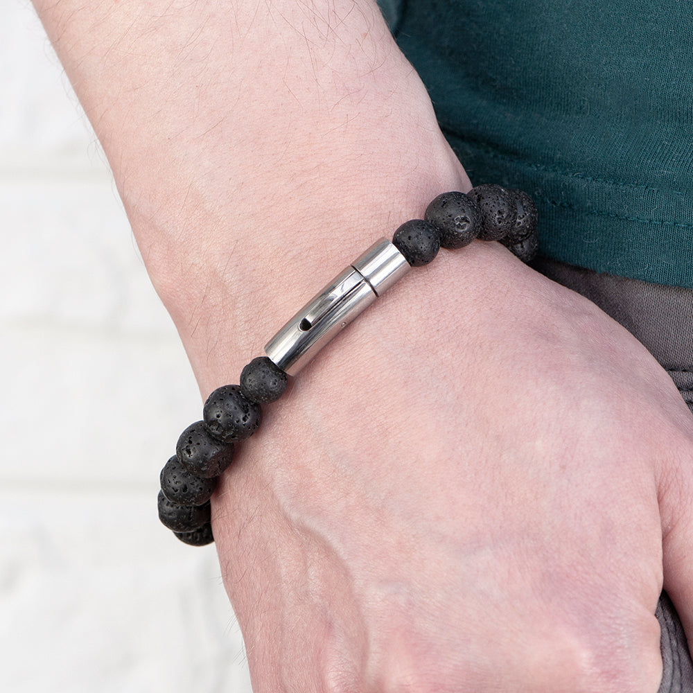 Bracelet with black beads and silver clasp on a wrist against a white background