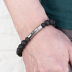 Bracelet with black beads and silver clasp on a wrist against a white background