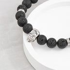Black beaded bracelet with a silver skull charm on a white plate