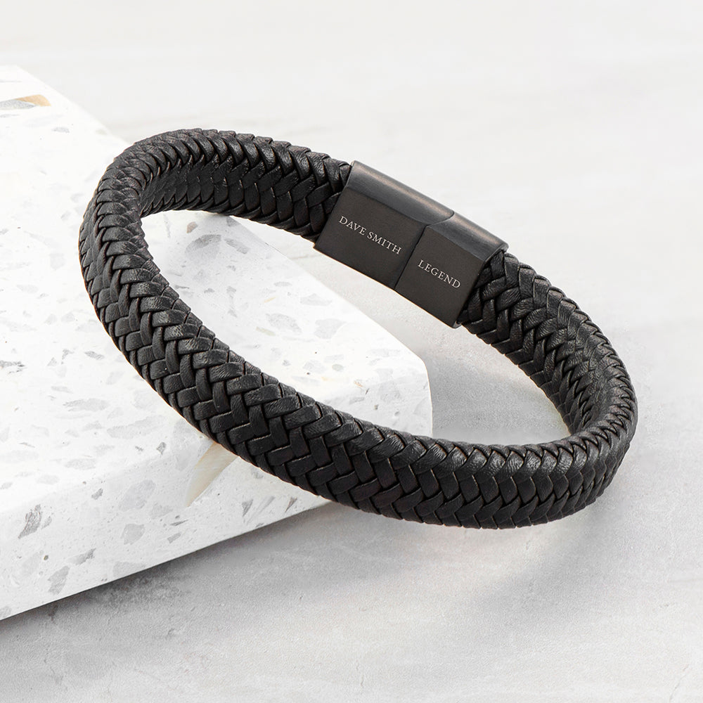 Black braided bracelet with a clasp on a light gray background