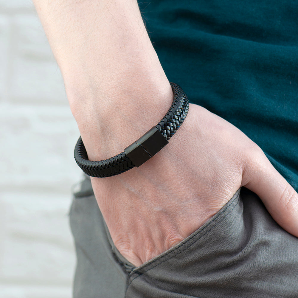 Person wearing a black braided bracelet on a blurred background
