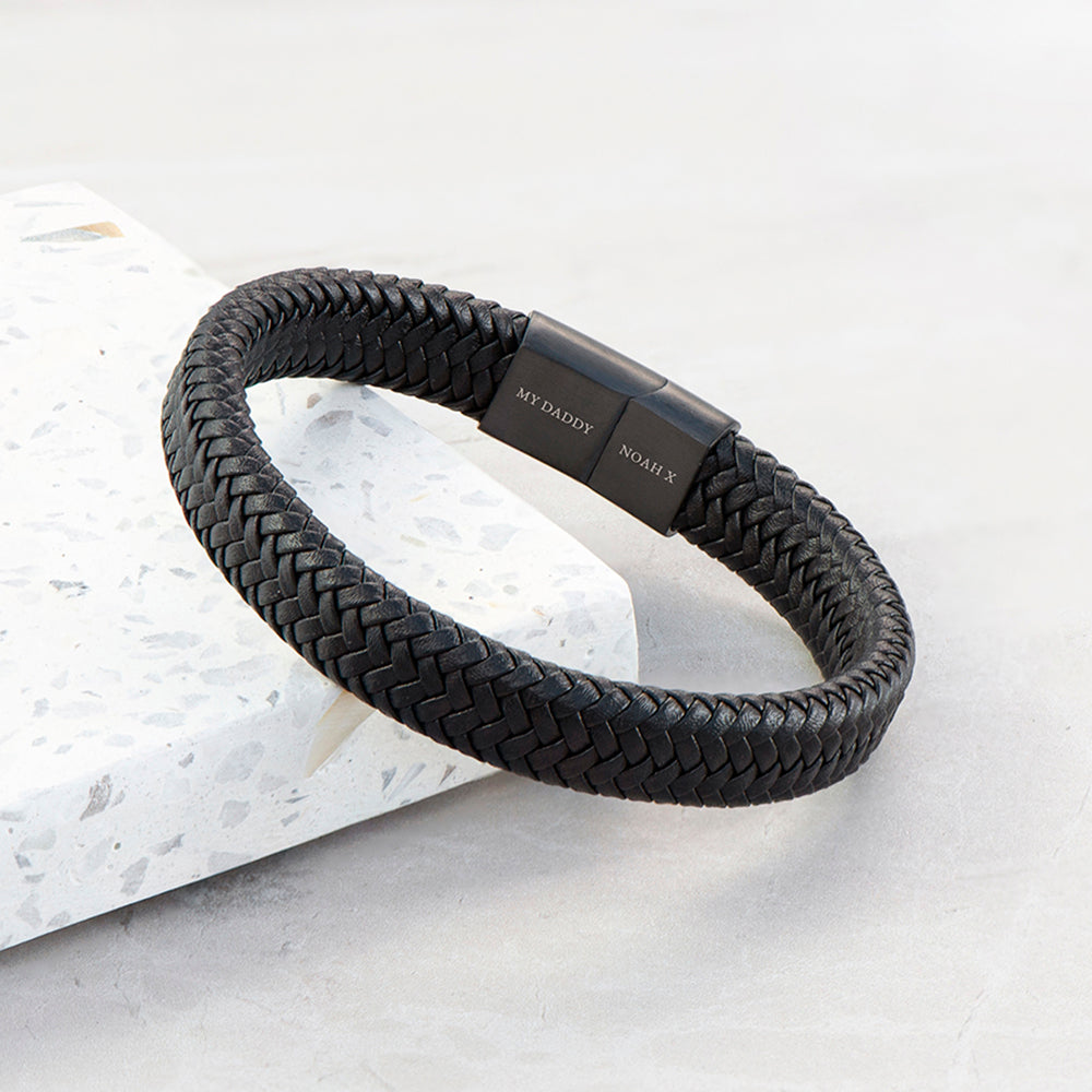Black braided bracelet with engraved text on a light gray background