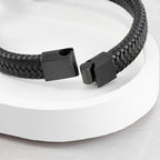 Black braided bracelet with a clasp on a white background