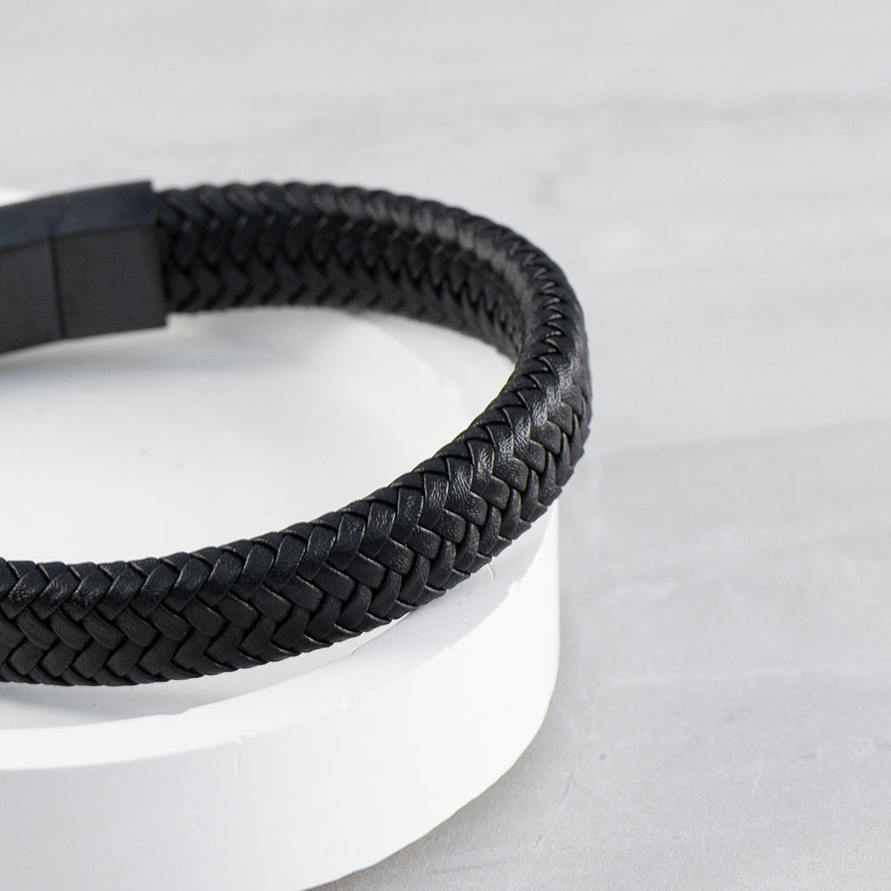 Black braided leather belt on a light gray background