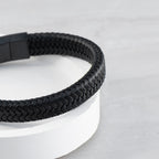 Black braided leather belt on a light gray background