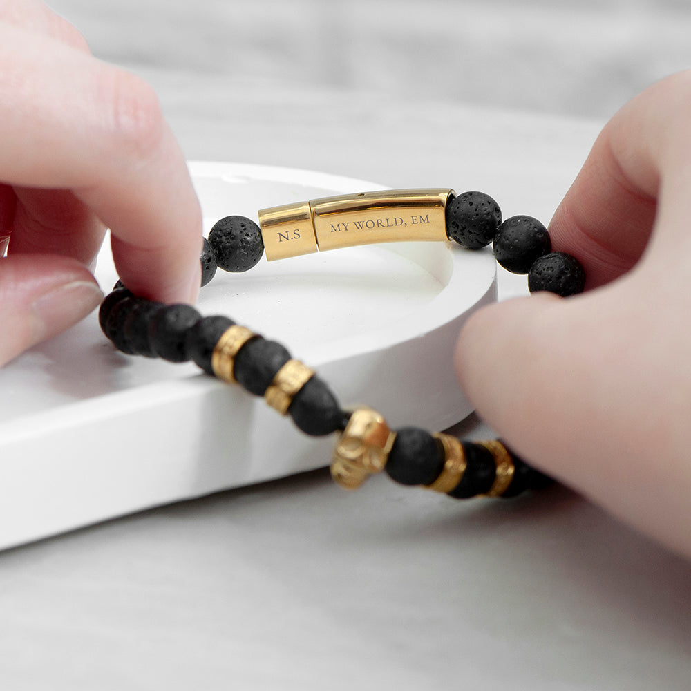 Black beaded bracelet with gold accents held by hands on a light background