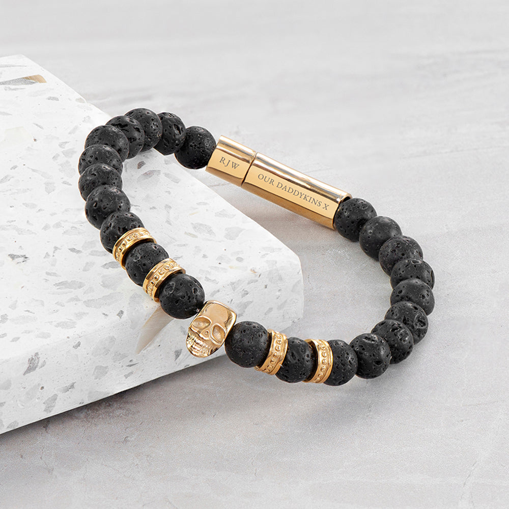 Black beaded bracelet with gold accents on a light gray surface