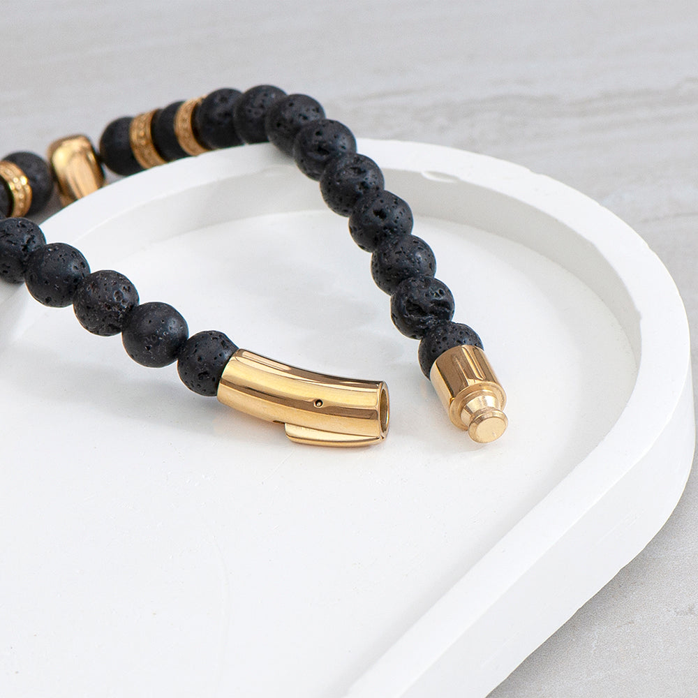 Black beaded bracelet with gold accents on a white surface