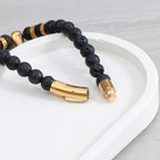 Black beaded bracelet with gold accents on a white surface