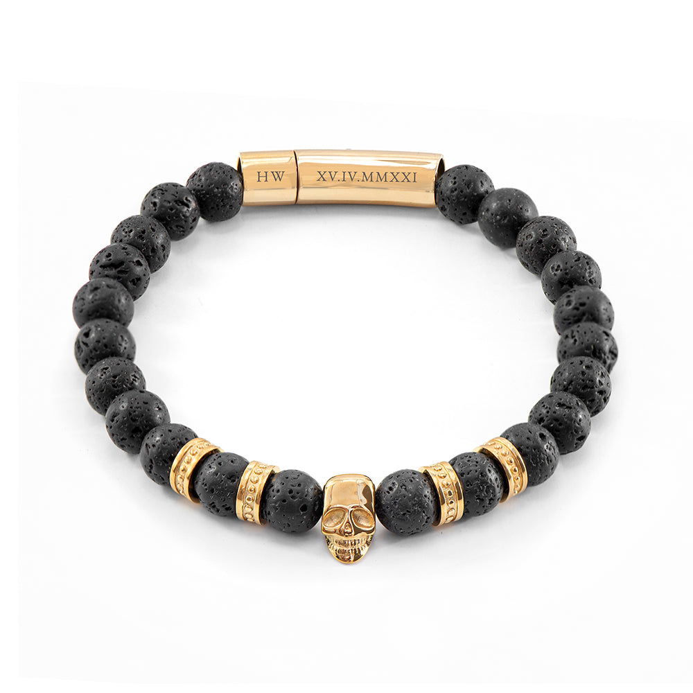 Black beaded bracelet with gold accents and a skull charm on a white background