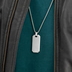Silver dog tag necklace on a green shirt with a black leather jacket