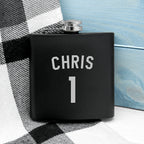 Black flask with 'CHRIS' and number '1' on a checkered fabric background