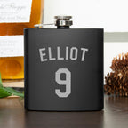 Black flask with 'ELLiot 9' engraving on a wooden surface