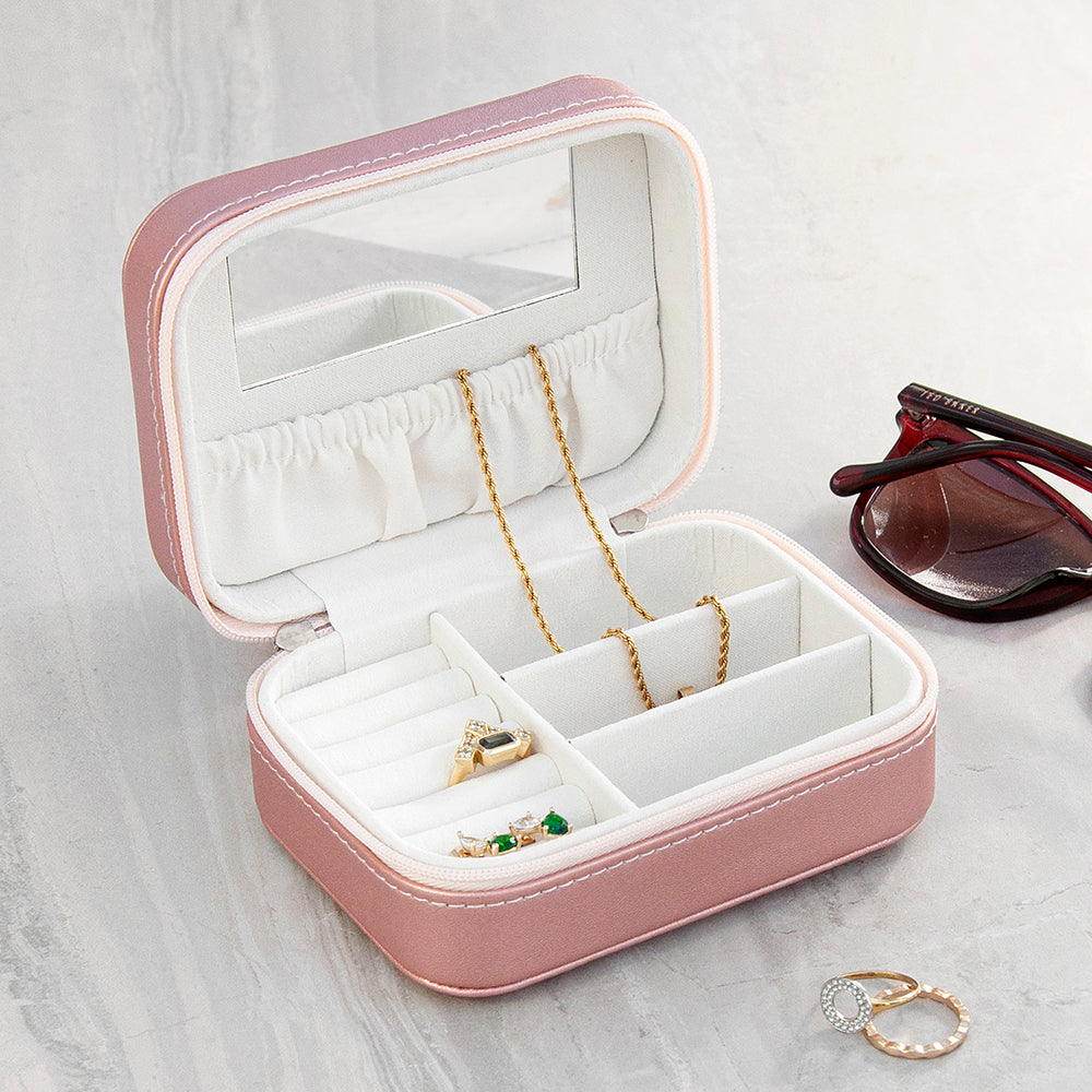Pink jewelry box with jewelry on a light gray surface