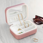 Pink jewelry box with jewelry on a light gray surface