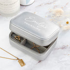 Gray jewelry case with 'Emily's Treasure' engraving on a marble surface with gold necklaces.