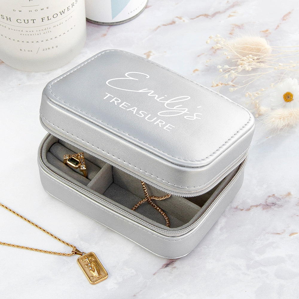 Gray jewelry case with 'Emily's Treasure' engraving on a marble surface with gold necklaces.