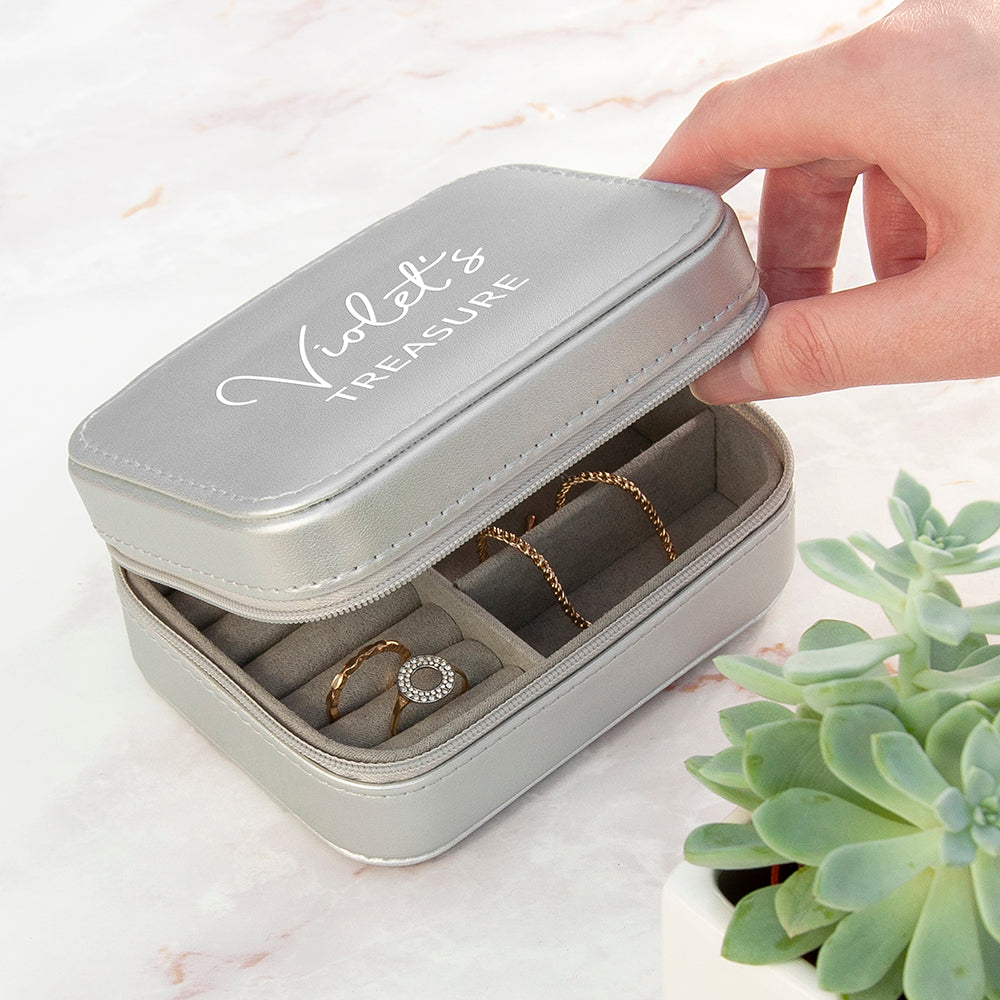 Gray jewelry case with 'Violet's Treasure' text, containing jewelry, on a light background.