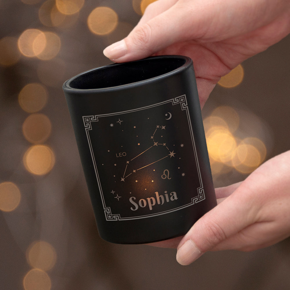 Black mug with star design and 'Olivia' text held by a hand against a blurred background