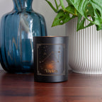 Black candle with 'Vivien' branding on a wooden surface with decorative items.