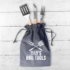 Set of BBQ tools in a drawstring bag with 'Dad's BBQ Tools' text on a wooden surface.
