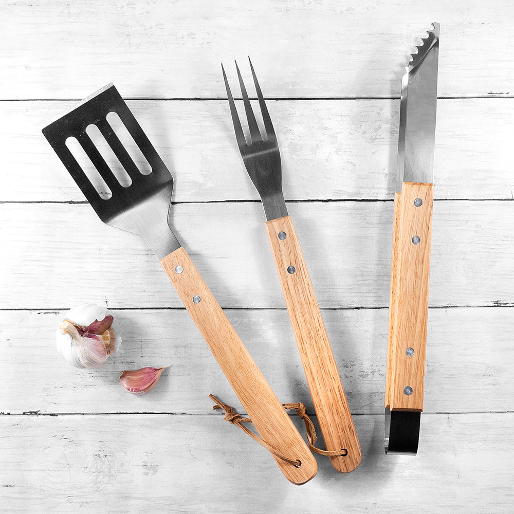 Set of wooden-handled barbecue tools on a light wooden surface
