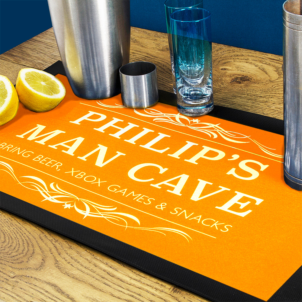 Personalized bar mat with 'Philip's Man Cave' text on a wooden surface with bar items.