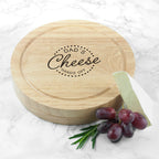 Wooden cheese board with 'Dad's Cheese Hands Off' engraving on a marble surface with grapes and a wedge of cheese.