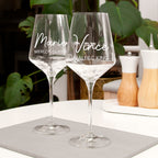 Two personalized wine glasses on a table with a blurred background
