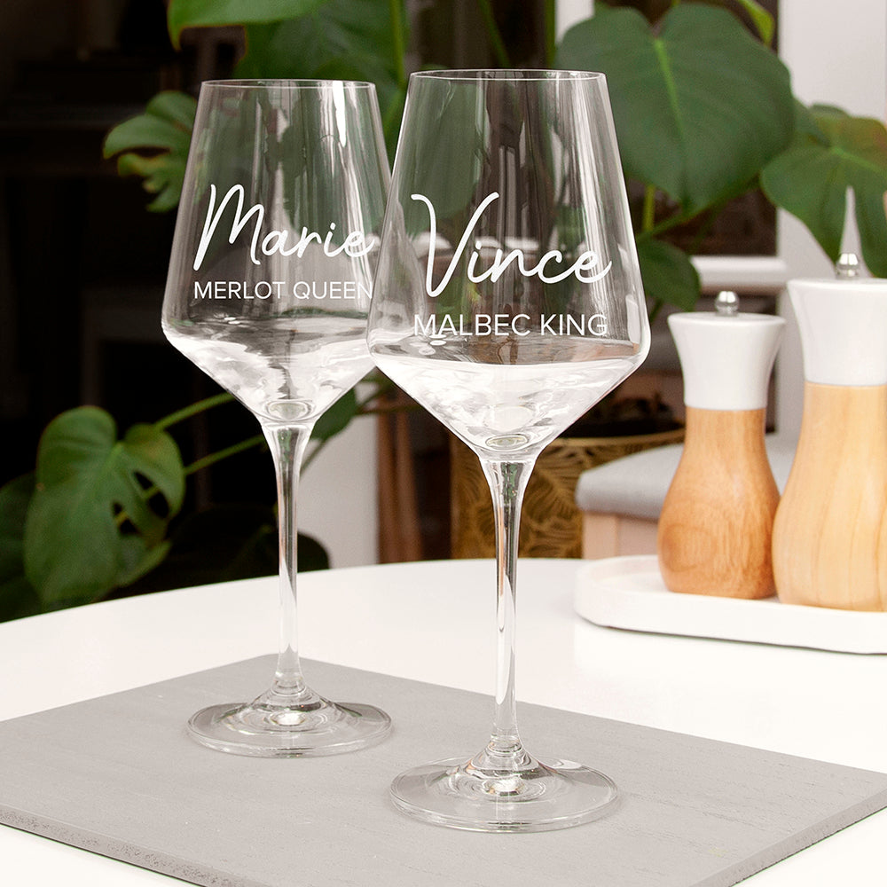 Two personalized wine glasses on a table with a blurred background