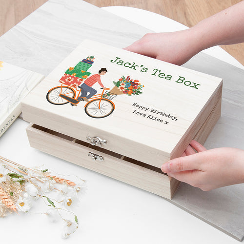 Wooden tea box with 'Jack's Tea Box' branding and a bicycle illustration, held by a person.
