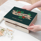 Tea box with decorative lid and text, held by a hand on a light surface.