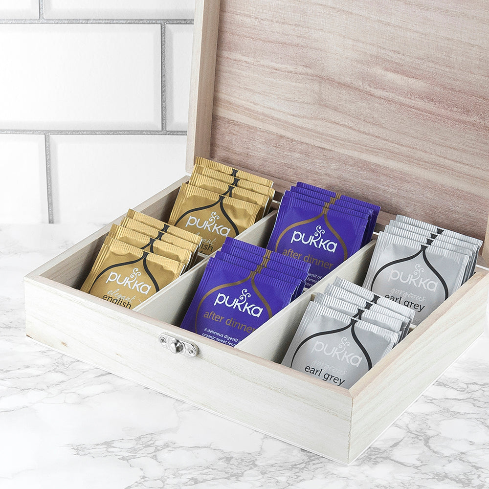 Pukka tea bags in a wooden box on a marble surface