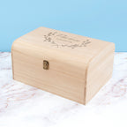 Wooden box with engraved text on a marble surface with a light blue background