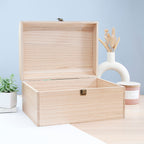 Wooden jewelry box on a light surface with a plant and candle in the background