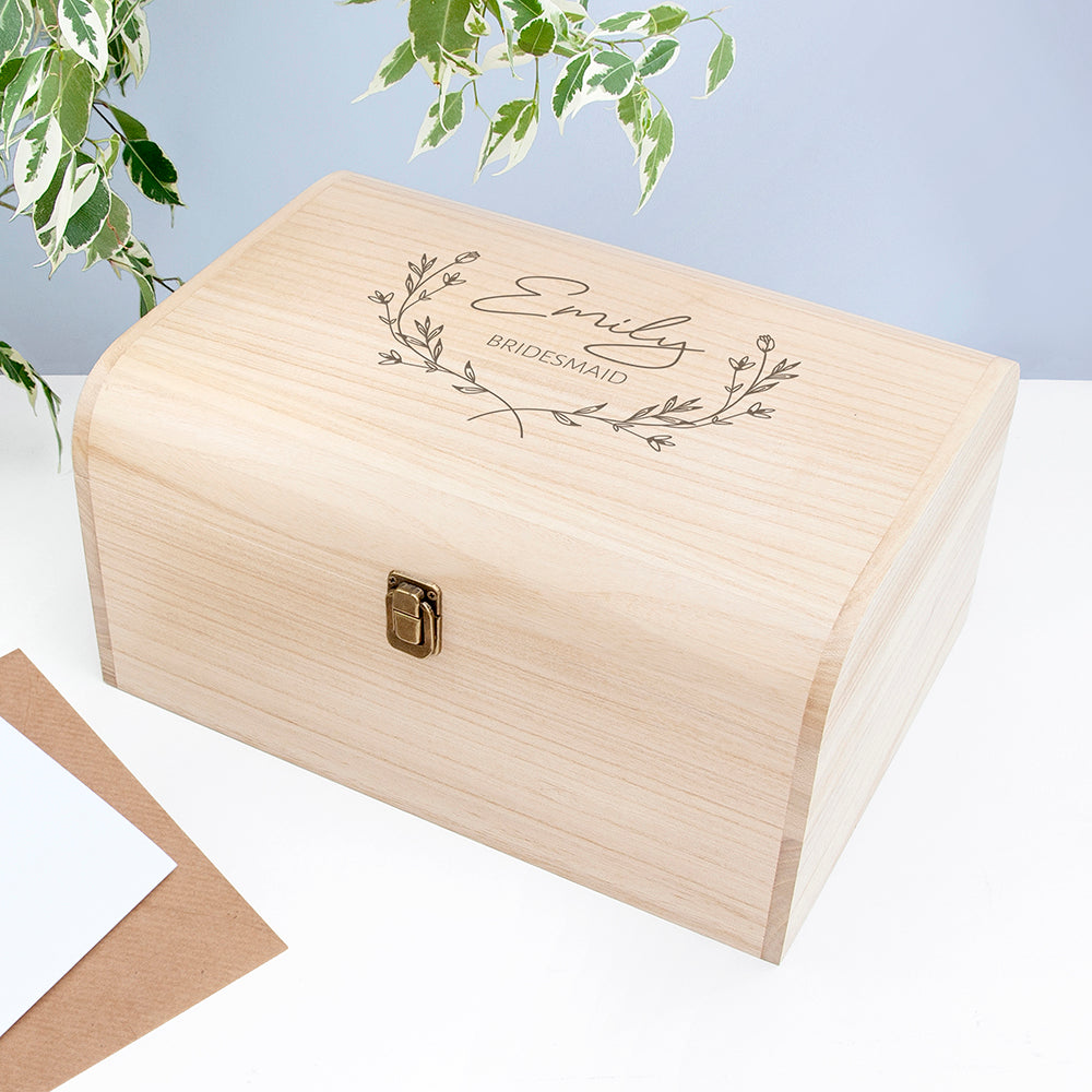 Wooden box with engraved text and floral design on a light blue background