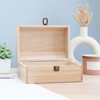 Wooden jewelry box on a table with decorative items including a vase with dried flowers and a candle.