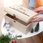 Wooden gift box with 'Olivia' engraved, surrounded by Christmas decorations on a table.