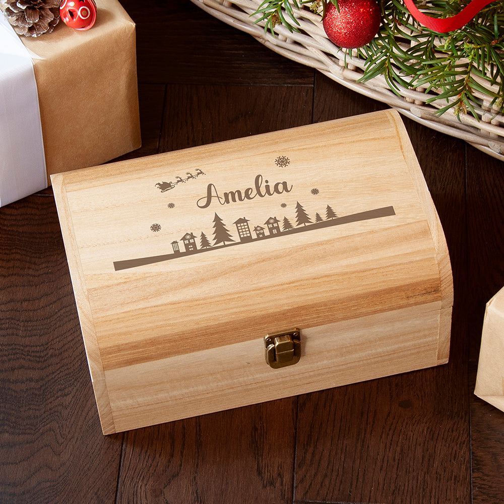 Wooden box with engraved design and name 'Amelia' on a wooden surface with Christmas decorations.
