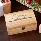 Wooden box with engraved design and name 'Amelia' on a wooden surface with Christmas decorations.
