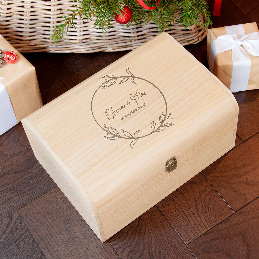 Wooden gift box with engraved design on a wooden floor with Christmas decorations.