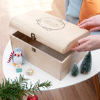 Wooden gift box with a penguin ornament on a table with Christmas decorations.