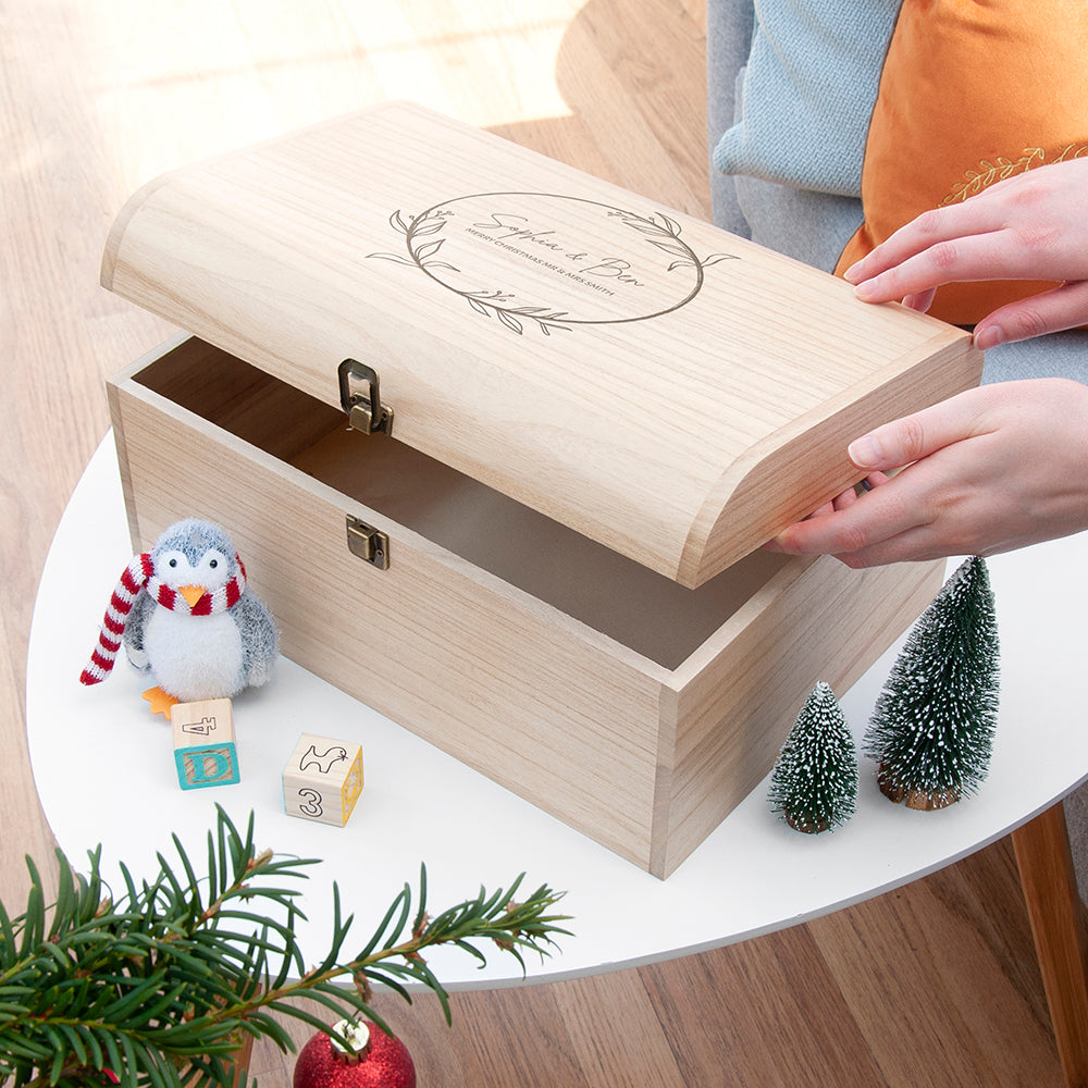Wooden gift box with a penguin ornament on a table with Christmas decorations.