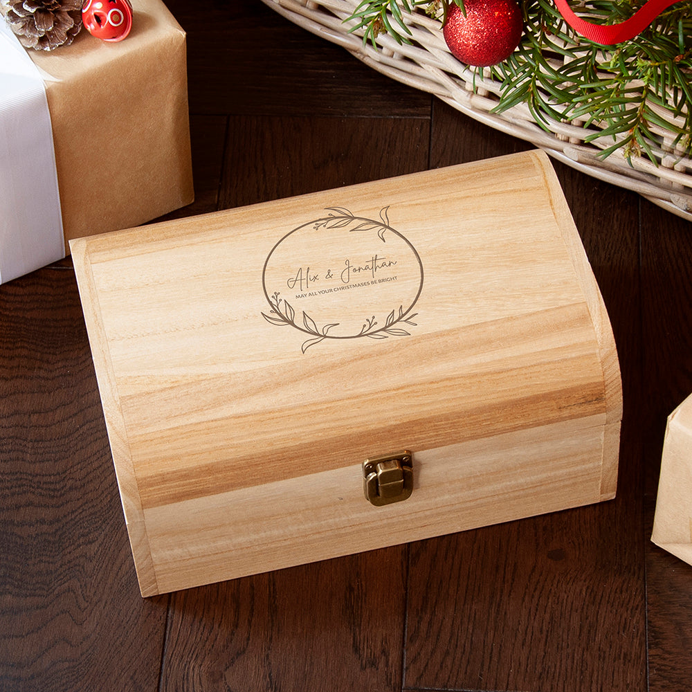 Wooden box with engraved design on a wooden surface with Christmas decorations.