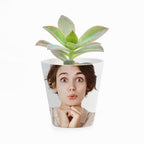 Potted plant with a face printed on the pot against a white background
