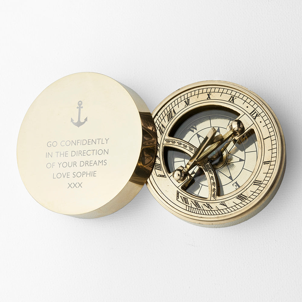 Brass compass with engraved message on a white background