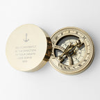 Brass compass with engraved message on a white background