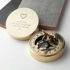 Brass compass with engraved message on a white surface
